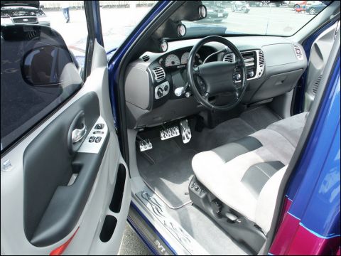 2001 Mercury Grand Marquis - The interior of a blue pickup truck features custom pedals, a modified dashboard, and two-tone seats, suggesting a personalized build.