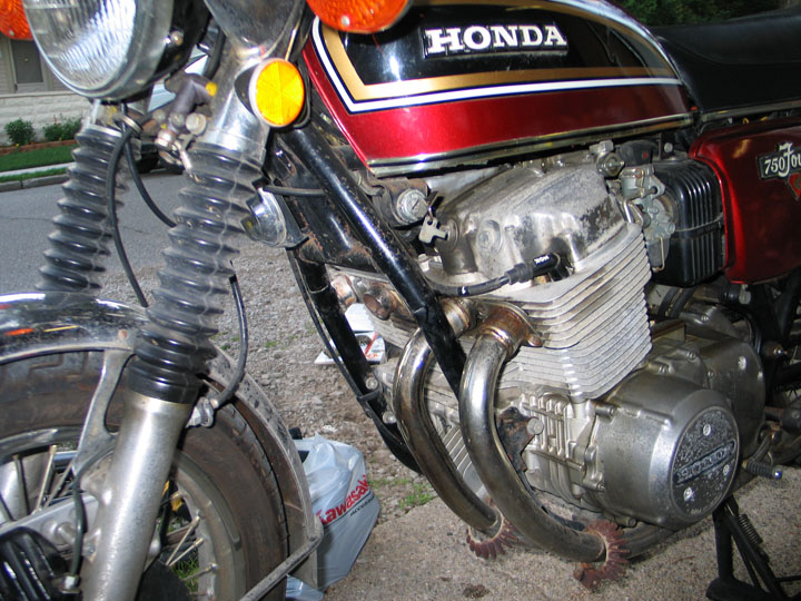 Honda motorcycle engine with "750 Four" visible on the side cover. Front fork and part of the fuel tank are also visible