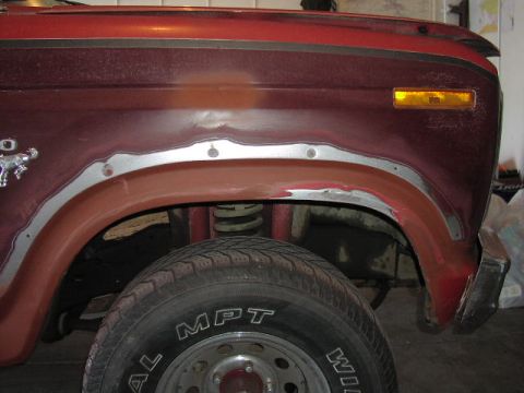 1981 Ford Bronco - Close-up of the fender and wheel well area of a red 1980 Ford Bronco, showing bodywork in progress.