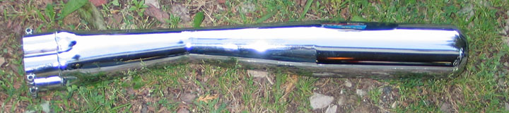 Chrome exhaust pipe with dual outlets, lying on grass