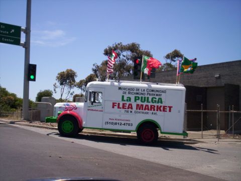 1989 Ford Bronco - Side view of a vintage white box truck parked at a roadside, lettered "La Pulga Flea Market: Mercado de la Comunidad de Richmond Parkway, 7…