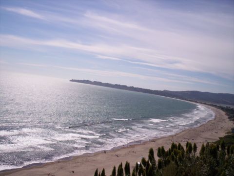1989 Ford Bronco - A scenic coastal view captures the expanse of the ocean meeting a populated beach, with rolling hills in the background.