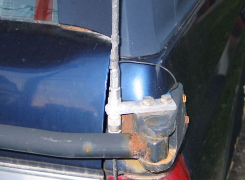 1994 Ford Bronco - Close-up of a rusted rear bumper mount and antenna on a blue SUV.