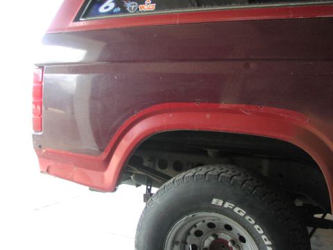 1981 Ford Bronco - Rear view of a red 1981 Ford Bronco, showing the quarter panel, fender flare, and tire.