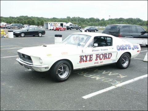 2001 Mercury Grand Marquis - A white 1967 Ford Mustang Cobra Jet with RYE FORD livery is parked at an outdoor car show.