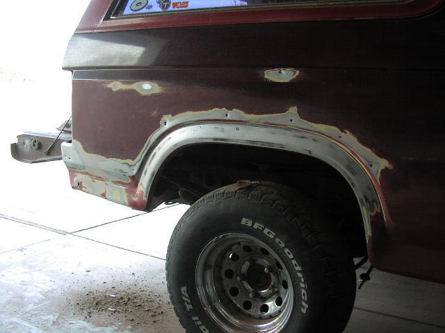 Maroon SUV rear quarter with sanded paint and body filler around wheel arch