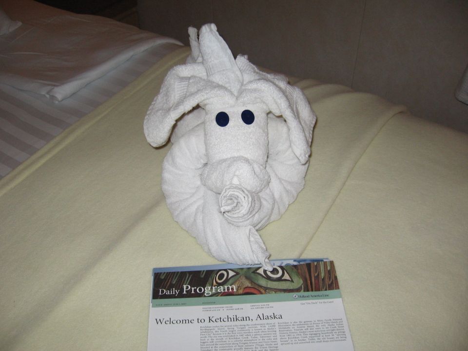 Towel animal on a bed with a 'Welcome to Ketchikan, Alaska' daily program