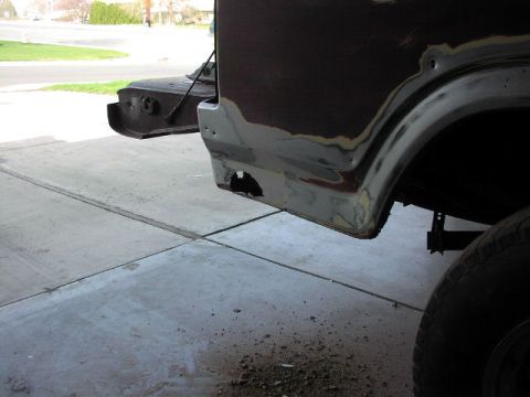1981 Ford Bronco - The rear quarter panel of a vehicle is shown with primer and evidence of rust repair.
