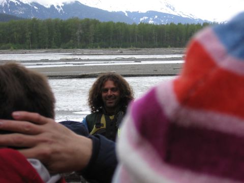 1973 Ford Ranchero - People gathered by a river with a forested bank and mountains under a cloudy sky.