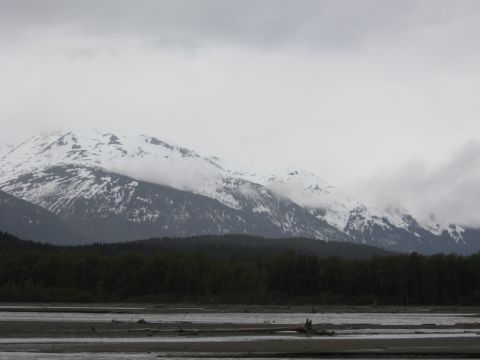 1973 Ford Ranchero - A cloudy day over a vast landscape with snow-covered peaks, dense trees, and a wide, rocky river.