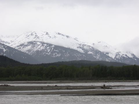 1973 Ford Ranchero - A vast landscape of snow-covered mountains dominates the background, with a dense forest and a river in the foreground.