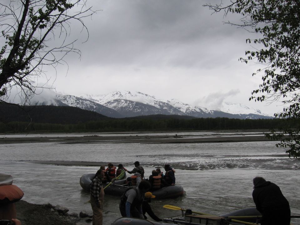 Rafting group on a river with snow-capped mountains in the background