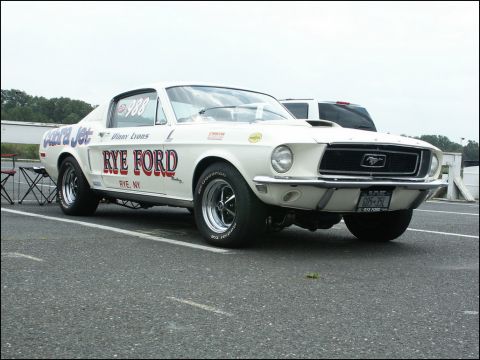 2001 Mercury Grand Marquis - A classic Ford Mustang drag car, identified by its 'Cobra Jet' and 'Rye Ford' livery, is parked on a paved surface.