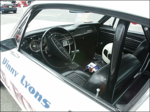 2001 Mercury Grand Marquis - The interior of a classic white car, possibly a 1967 Mustang, is visible with racing seats and a roll cage.
