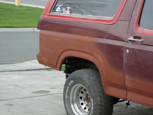 Faded two-tone red SUV rear quarter panel with Trail T/A tire on polished mag wheel