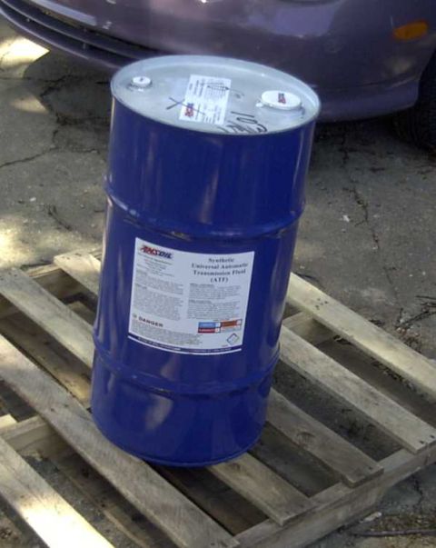 1997 Ford Taurus - A blue barrel of transmission fluid sits on wooden pallets, partially obscuring a purple vehicle fender.