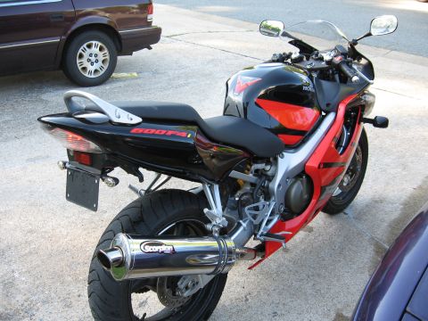 2004 Honda CBR600F - The rear of a red and black 2004 Honda CBR600F sportbike is shown, a Scorpion exhaust system.