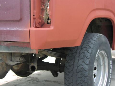 1981 Ford Bronco - Side view of a red truck's rear fender and wheel, showing suspension and bodywork.