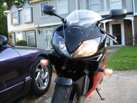 2004 Honda CBR600F - A Honda motorcycle is parked next to a car in front of townhouses.