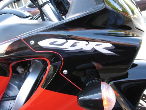 2004 Honda CBR600F - Close-up of a motorcycle's black fairing displaying the white 'CBR' logo, accented with red trim.