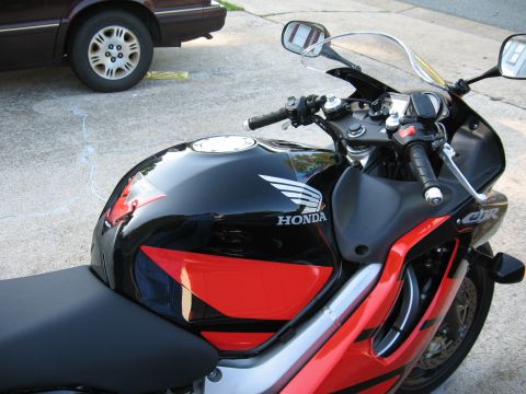2004 Honda CBR600F - A black and red Honda CBR600F motorcycle is parked on a concrete surface next to a car.