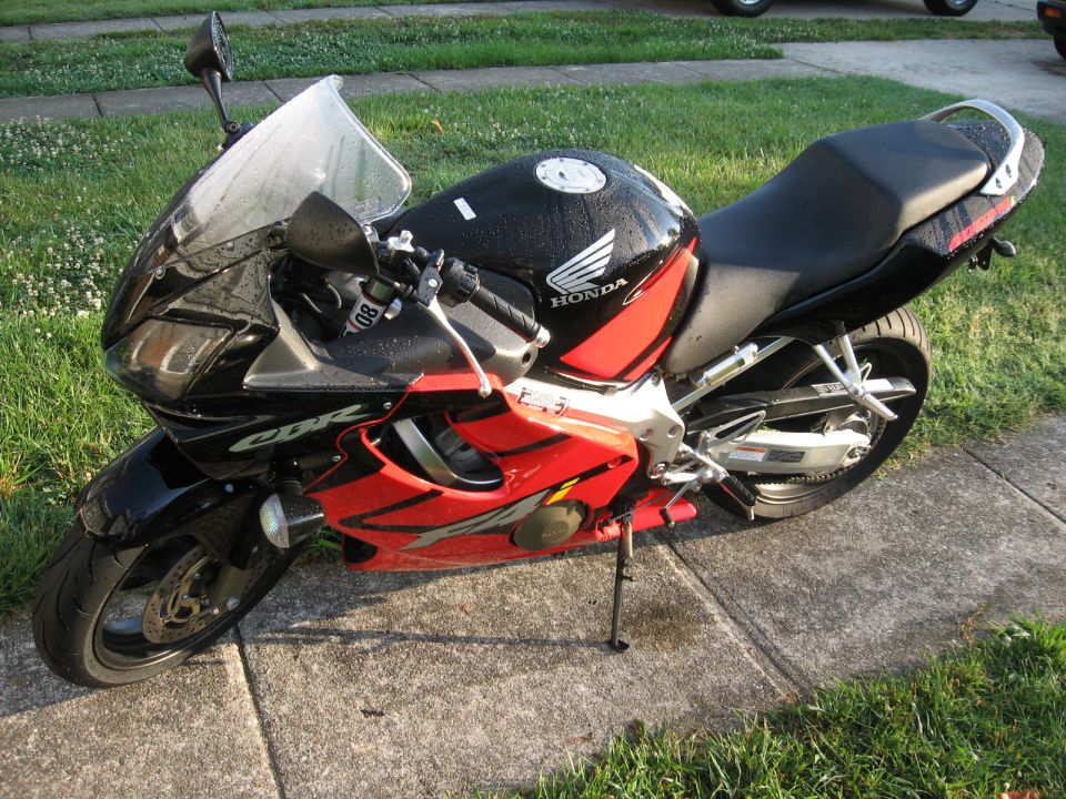 2004 Honda CBR600F motorcycle parked on a sidewalk, black and red fairings, Honda logo on tank