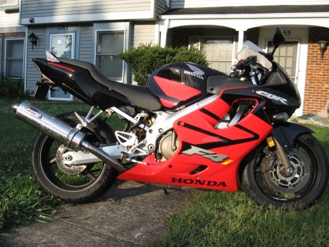 2004 Honda CBR600F - A red and black Honda CBR F4 motorcycle is parked on a sidewalk with grass in front of a house.