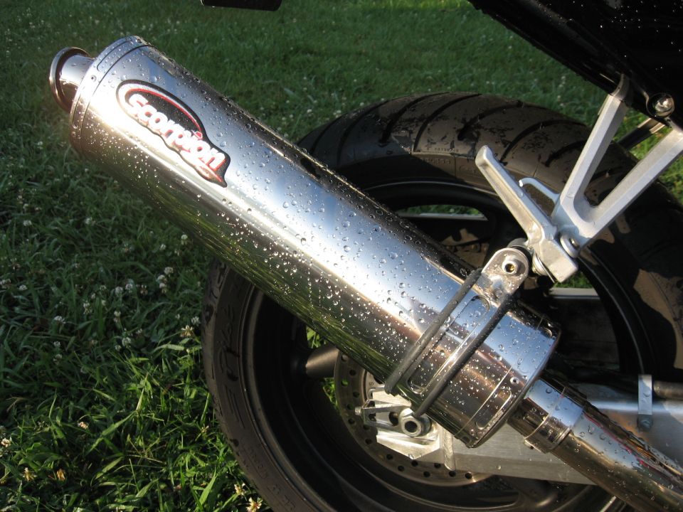 Close-up of a chrome Scorpion exhaust pipe on a motorcycle, covered in water droplets