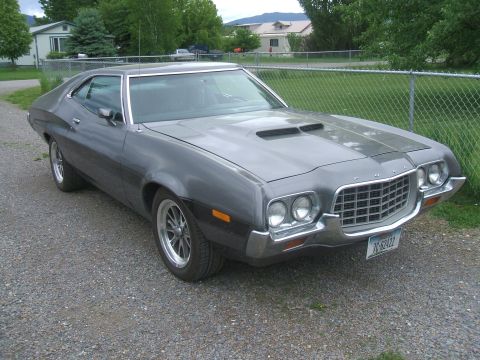 1974 Ford Ranchero - Front three-quarter view of a charcoal-gray Ford Torino-style hardtop coupe with a large chrome oval grille, dual round headlights per side…
