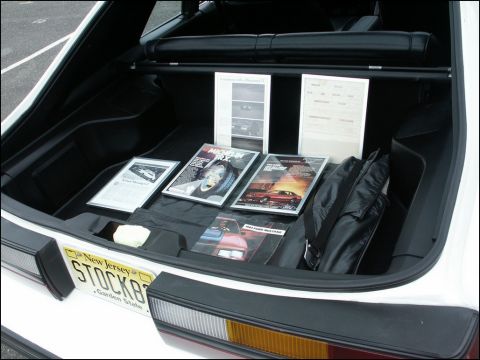 2001 Mercury Grand Marquis - The trunk of a white vehicle contains several magazines and documents, one of which is for a 1987 Ford Mustang.
