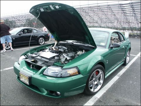 2001 Mercury Grand Marquis - A green Ford Mustang Cobra is displayed with its hood open, revealing the engine. A second car is visible in the background.