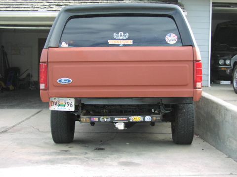 1981 Ford Bronco - Rear view of a red Ford Bronco with a black top, parked in a driveway.