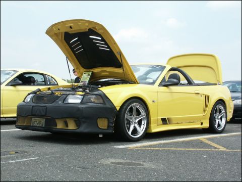 2001 Mercury Grand Marquis - Yellow convertible sports car with hood and trunk open, parked at a car show. Another yellow car is visible.