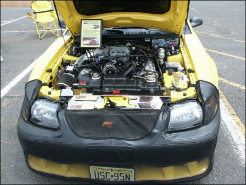 2001 Mercury Grand Marquis - The hood is open on a yellow car, revealing its engine and a sign with information about its modifications.
