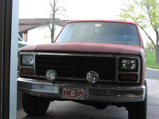 Front of a red square-body Ford with black grille, round driving lights and Fire Dept front plate