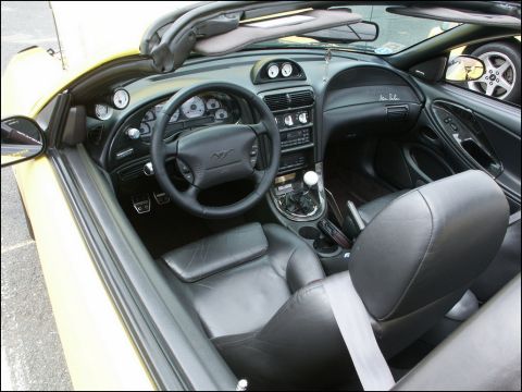2001 Mercury Grand Marquis - Black leather cockpit of a New Edge Mustang convertible, SVT Cobra emblem on steering wheel and a manual transmission shifter.