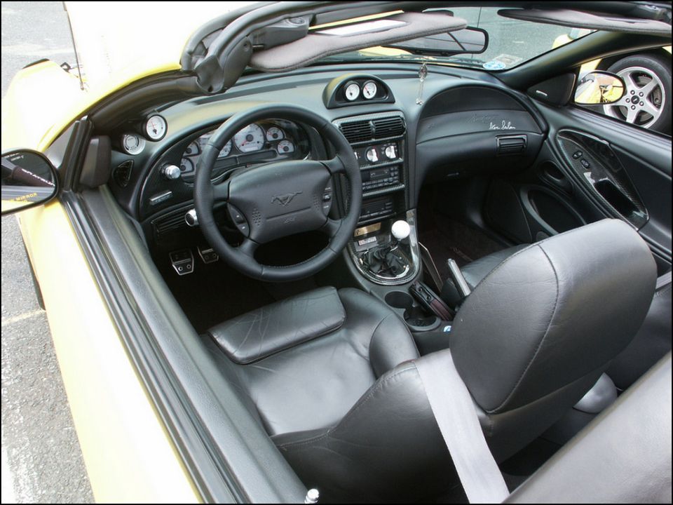 Black leather interior of a Ford Mustang convertible with manual shifter and SVT Cobra steering wheel