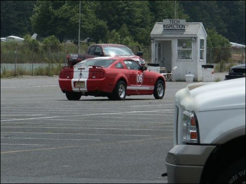 2001 Mercury Grand Marquis - A red coupe with white racing stripes and the number 06 on its side is parked in a lot near a tech inspection booth.
