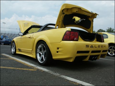 2001 Mercury Grand Marquis - Yellow Saleen Mustang convertible at a car show with hood and trunk open.