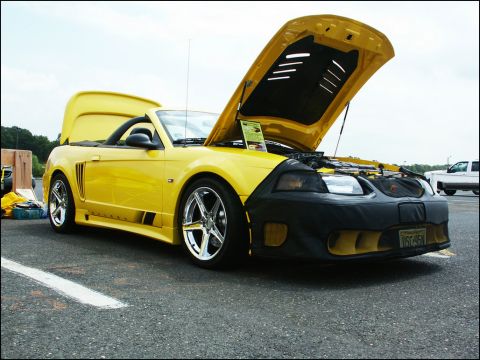 2001 Mercury Grand Marquis - A yellow convertible Mustang is displayed with its hood and trunk open at an outdoor event.