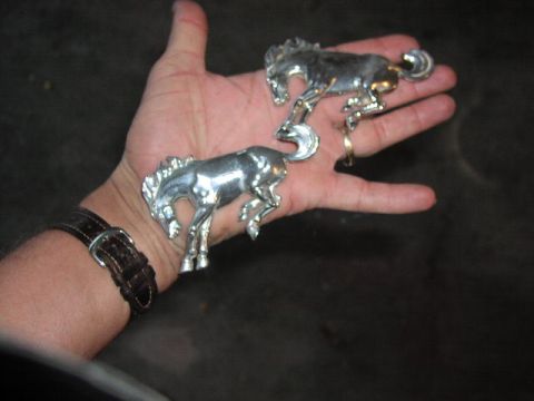 1981 Ford Bronco - Chrome horse emblems, possibly for a car's fender or grille, are displayed on a person's palm.
