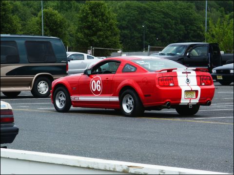 2001 Mercury Grand Marquis - A red Ford Mustang with racing stripes and the number 06 is parked in a lot with other vehicles.