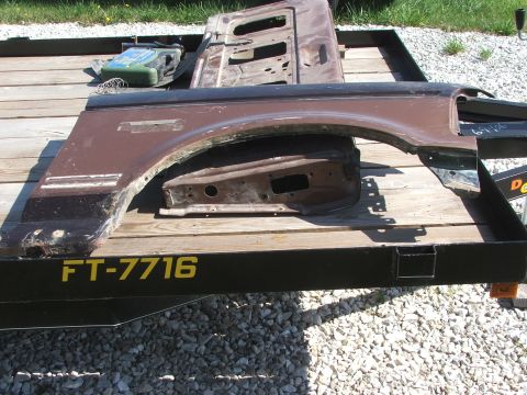 1994 Ford Bronco - Various brown body parts, including a fender and door sections, are loaded onto a trailer for sale.