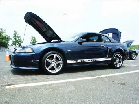 2001 Mercury Grand Marquis - A blue 2001 Ford Mustang GT is displayed with its hood and trunk open at a car show.