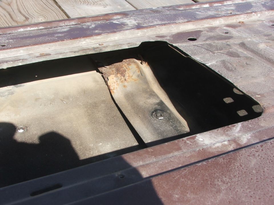 rusted metal panel with rectangular cutout showing internal bracing and some surface rust