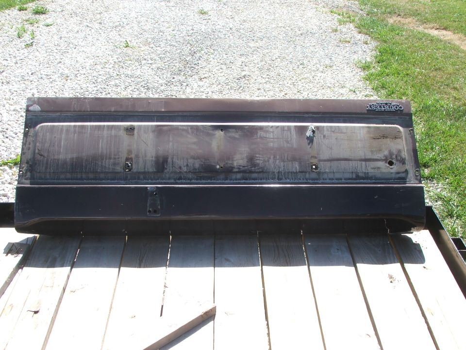 Tailgate with 'COUNTRY' badge on it, sitting on wooden planks