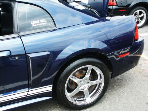 2001 Mercury Grand Marquis - A blue Ford Mustang is parked next to another vehicle, showing its side profile and custom decals.
