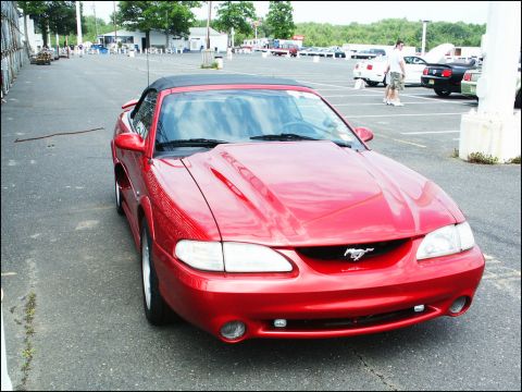 2001 Mercury Grand Marquis - Red convertible Mustang with a hood scoop and pony emblem is parked in an outdoor lot.
