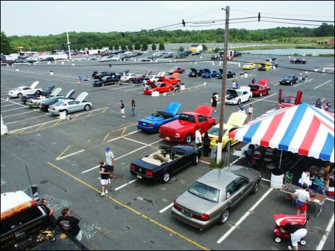 2001 Mercury Grand Marquis - A car show event with numerous vehicles displayed in a large parking lot under a tent.
