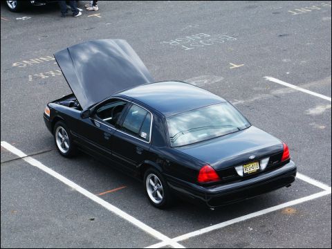 2001 Mercury Grand Marquis - A black sedan is parked in a lot with its hood open, revealing the engine bay.